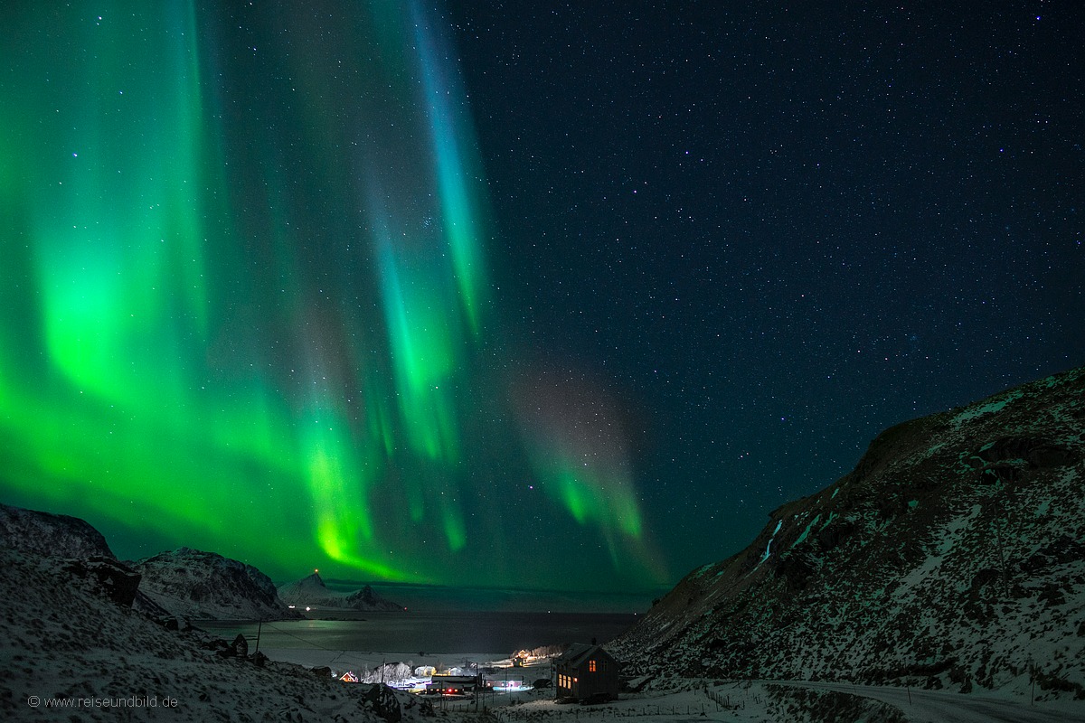 Unser Haus mit Polarlicht von der anderen Seite mit Bucht im Hintergrund